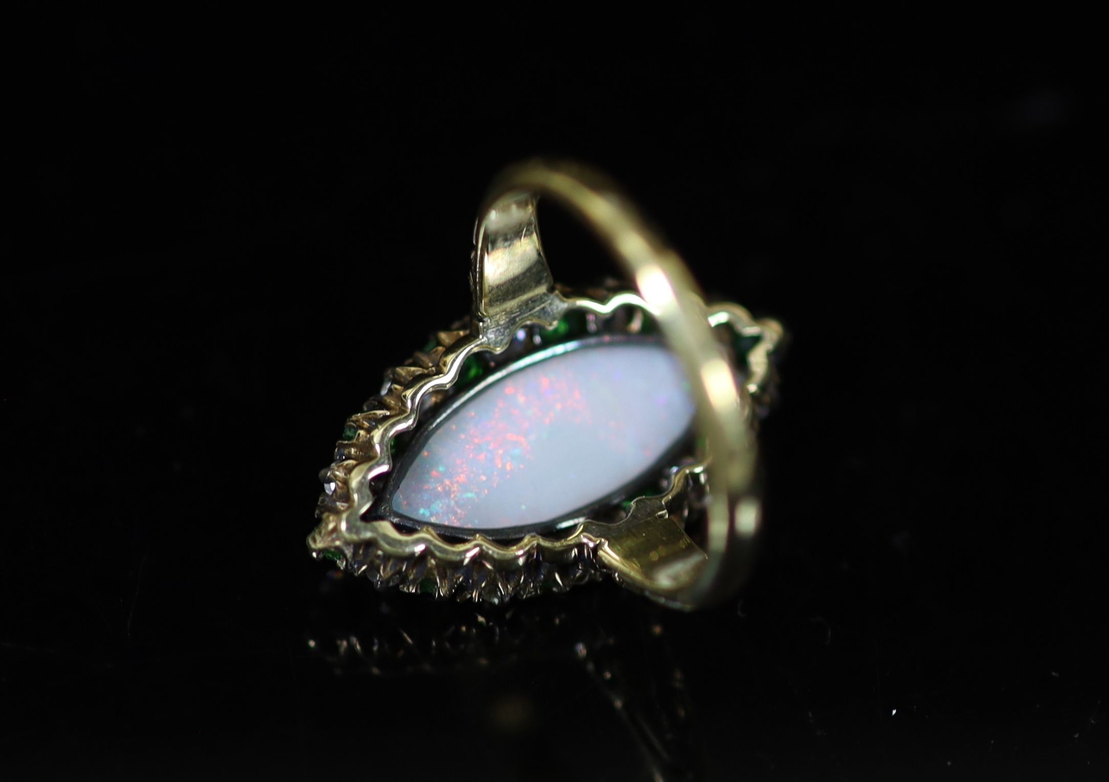 An early 20th century 18ct gold, white opal, green garnet and diamond set navette shaped dress ring